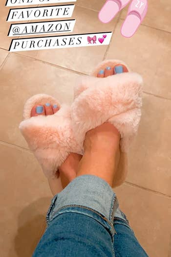 reviewer wearing the pink fuzzy slippers with the words 