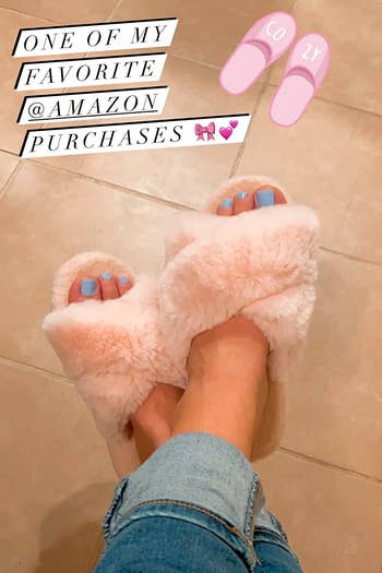 reviewer wearing the pink fuzzy slippers with the words 