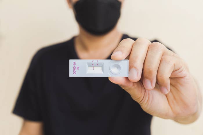 A man holds a rapid COVID antigen test kit displaying a negative result