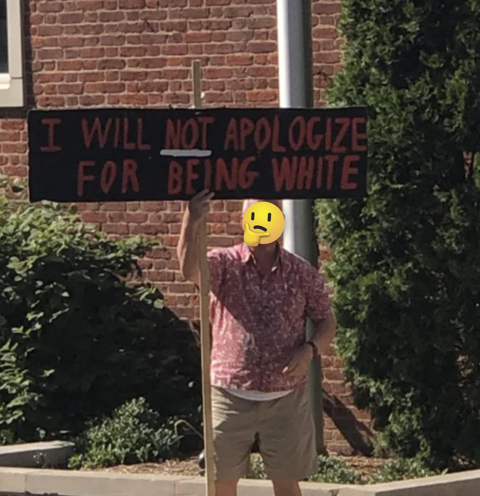 A man holding up a sign that says &quot;I will not apologize for being white&quot;
