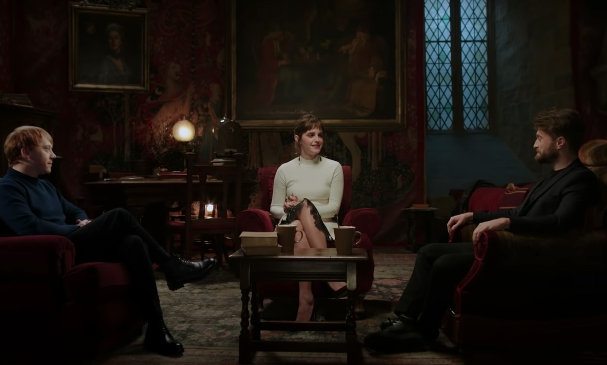Rupert Grint, Emma Watson and Daniel Radcliffe sitting together in a still from Harry Potter 20th Anniversary: Return to Hogwarts