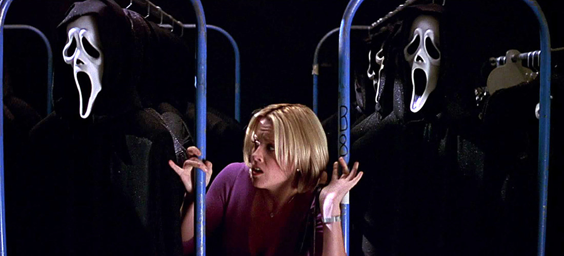 Jenna McCarthy as Sarah Darling, crouching between rows of Ghostface costumes