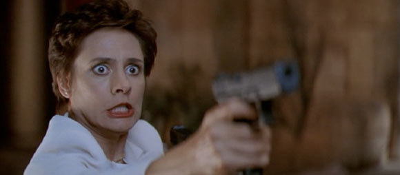 Mrs Loomis pointing a gun with a manic look in her eyes