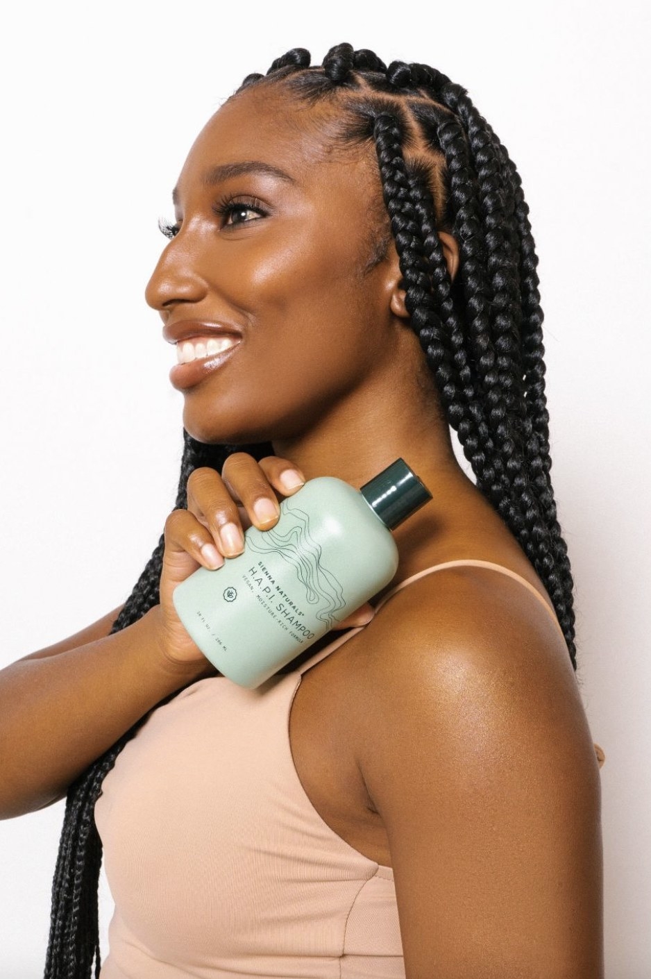 A person with braids holding a bottle of shampoo