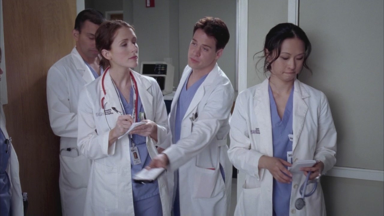 A Grey&#x27;s Anatomy screen cap showing George and three other interns, he is passing a notebook to someone