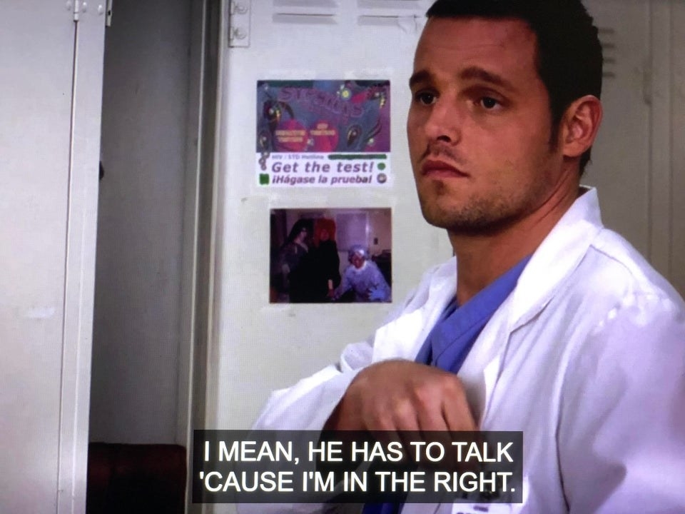 Alex standing in front of an open locker, which is decorated with a photo and a sticker saying &#x27;syphilis, get the test&#x27;