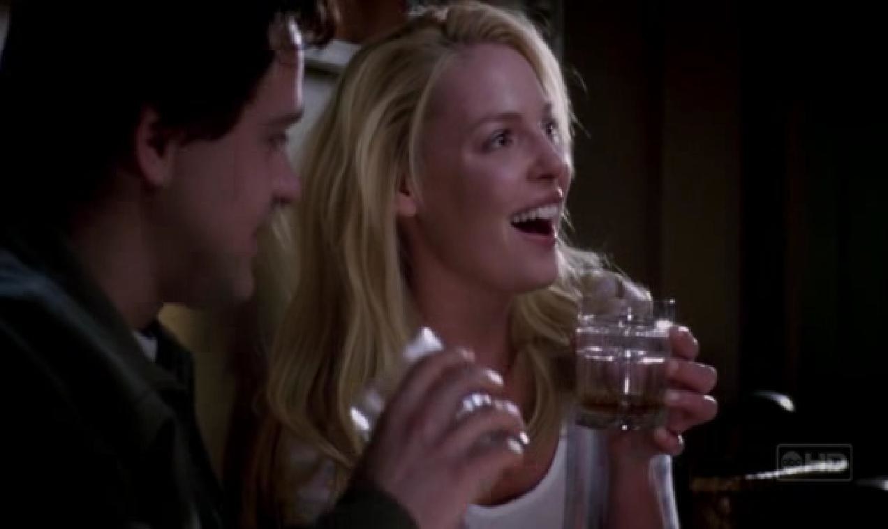 George and Izzie laughing and drinking from glasses at night