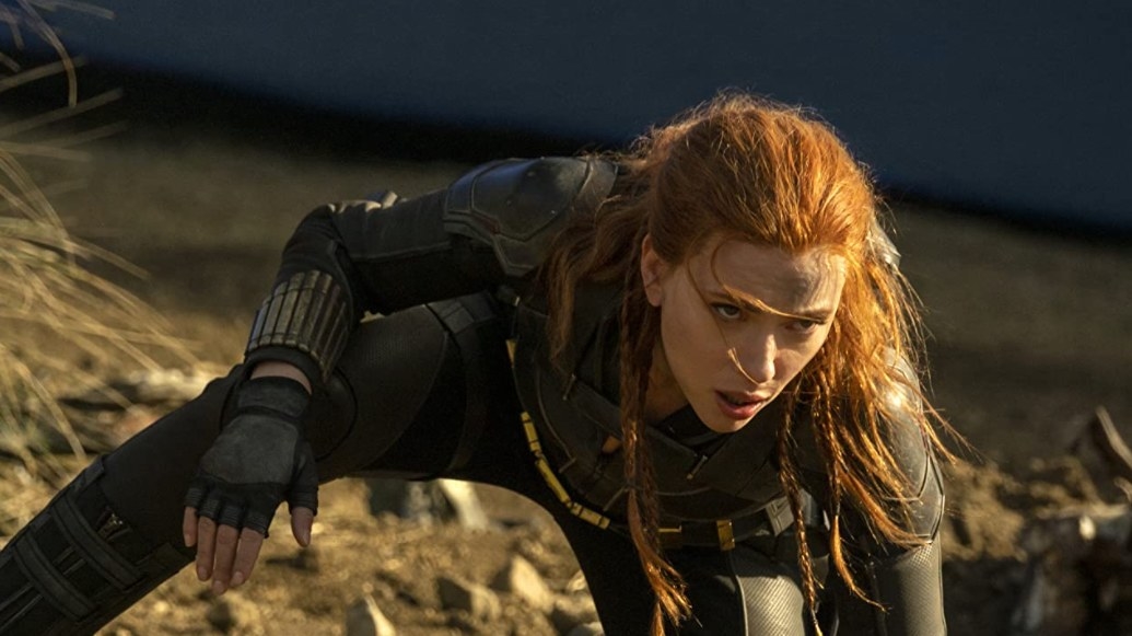 natasha wears a ponytail and leans forward in a field