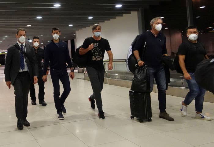 Novak walks with a group of men, all wearing masks