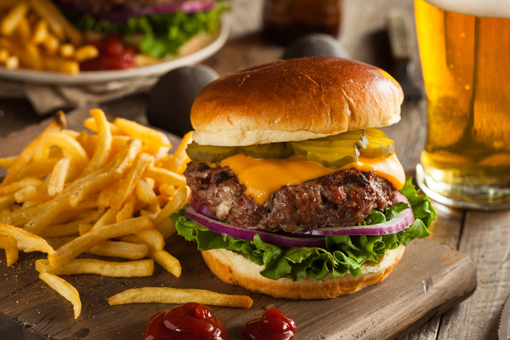 A burger with pickles, lettuce, cheese, and red onion with a side of fries and ketchup