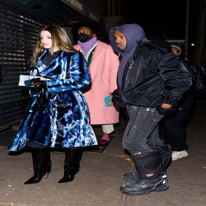 Paparazzi shot of Julia (L) and Kanye (R), the former is wearing a tie-dye overcoat and stiletto boots while the latter is wearing jeans, a hoodie, and rubber boots