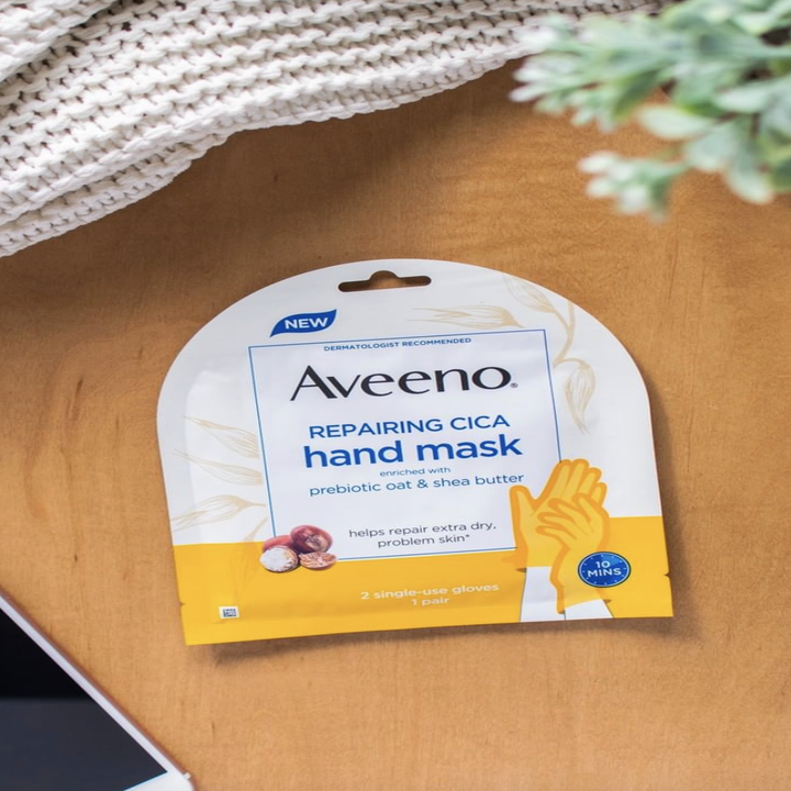 The hand mask in its packaging, on a surface with a smartphone