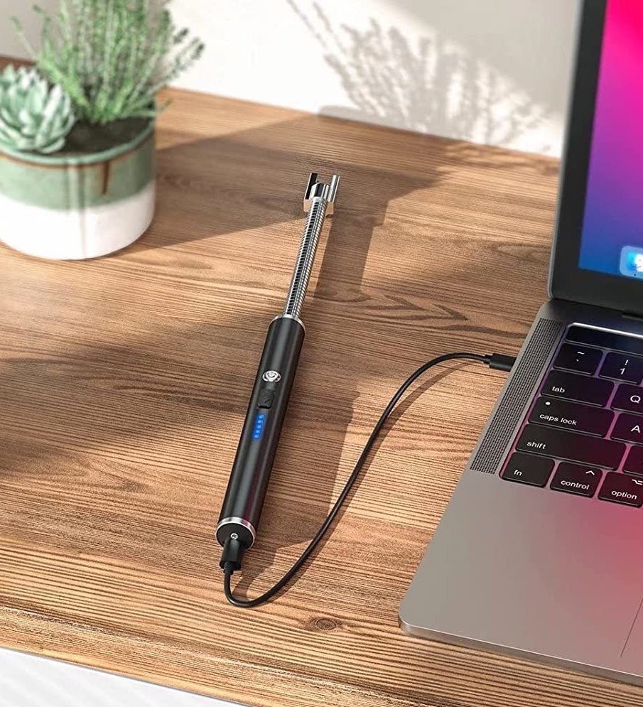 The lighter plugged into a laptop on a wooden table next to a plant
