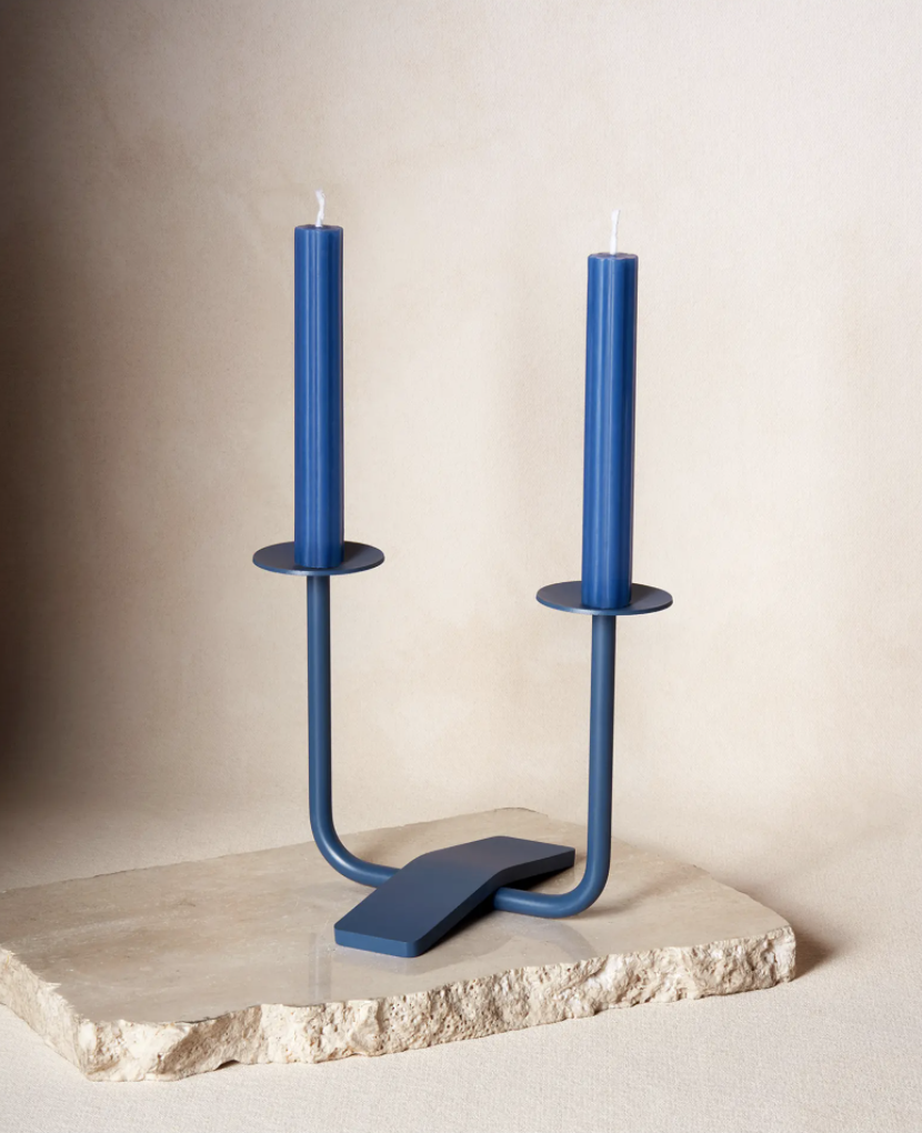 a two-prong powder coated steel candle holder on a slab of stone