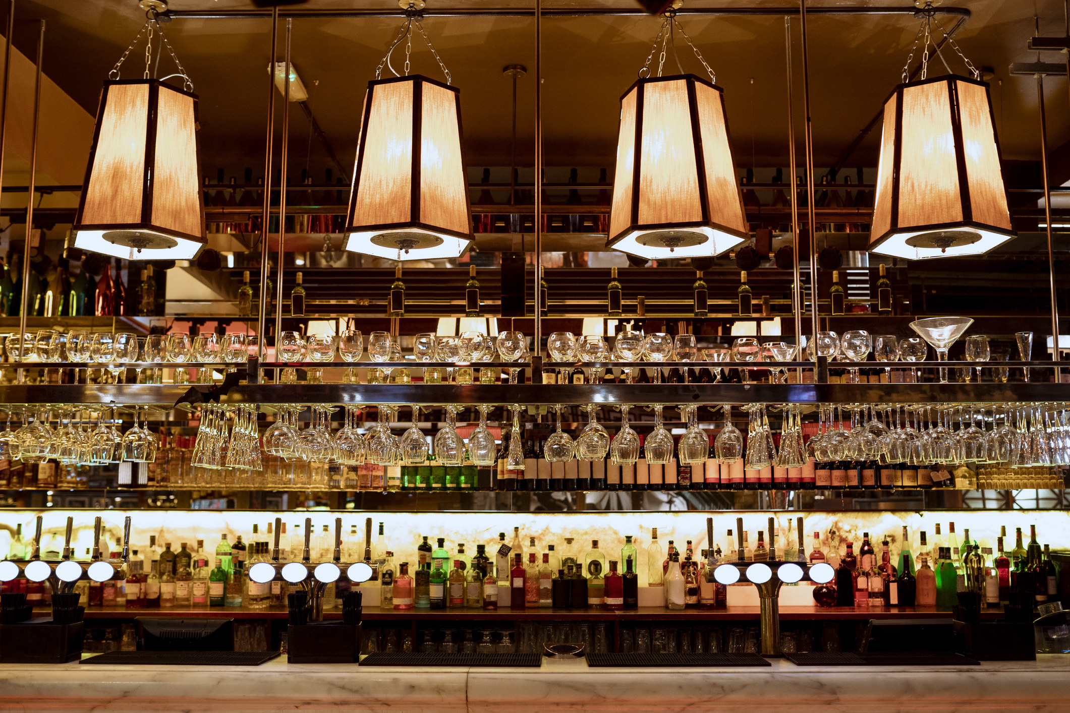 A stock image of a bar booth with bottles and glasses lining the shelves