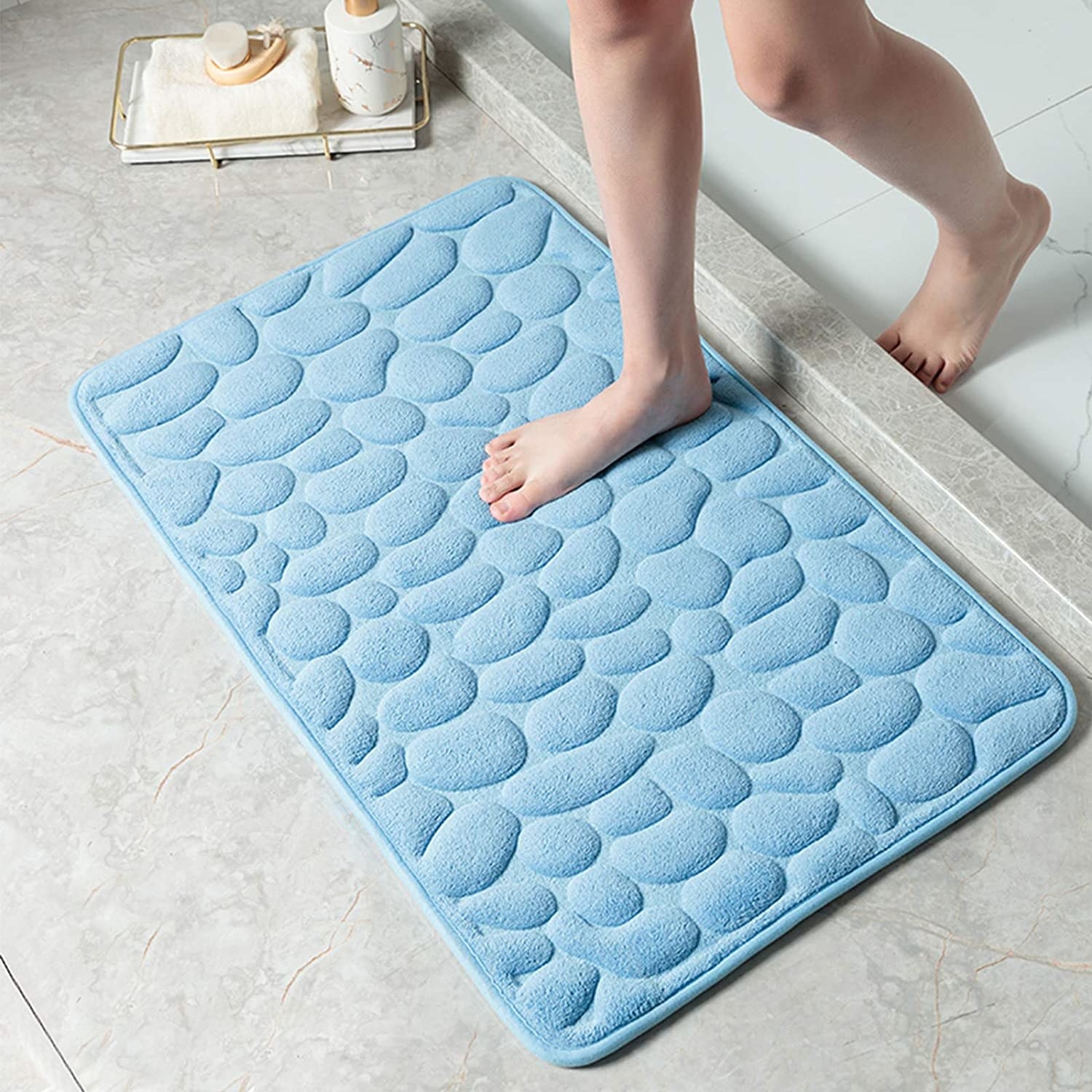 a person stepping onto the pebble-patterned memory foam bath mat