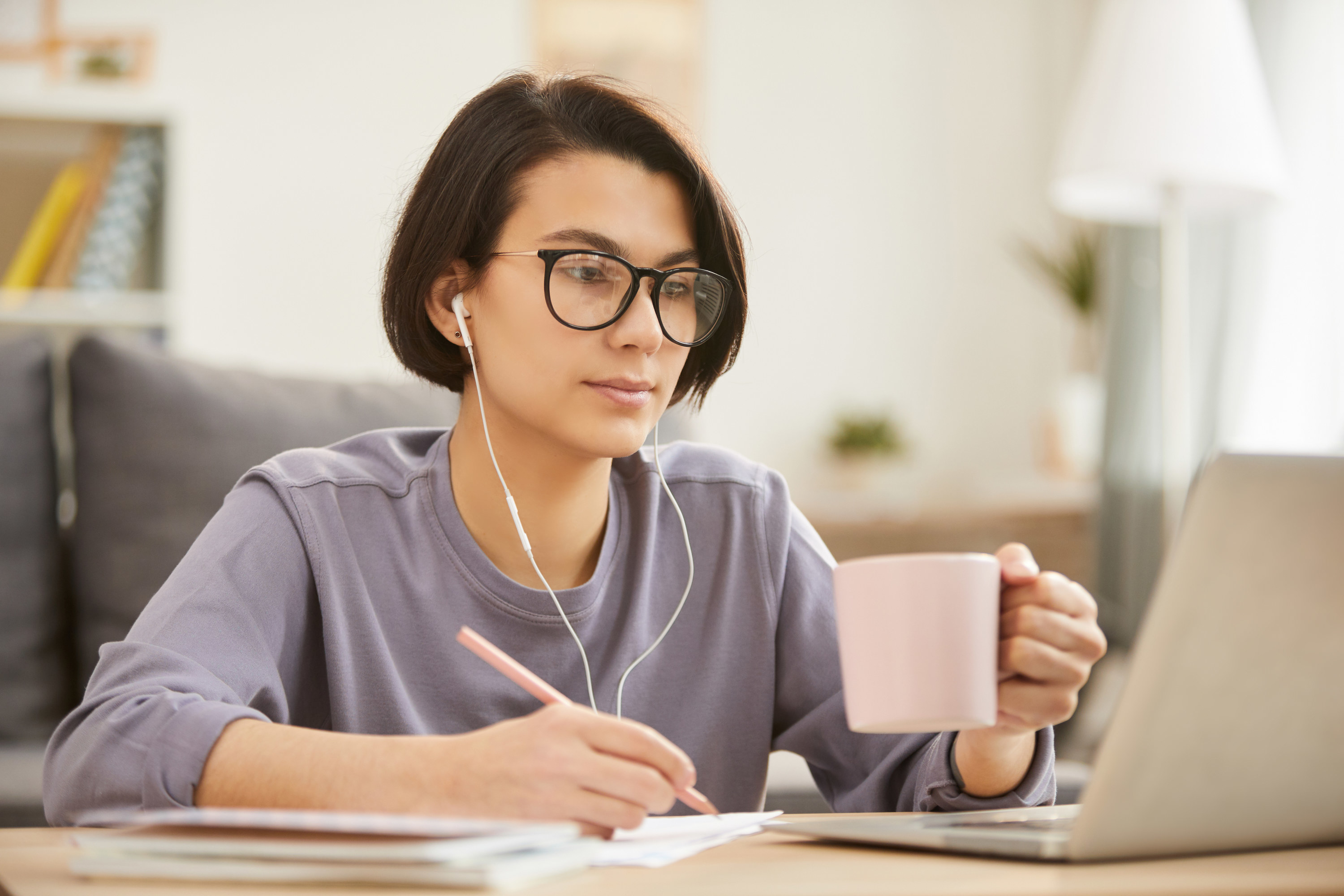 Woman with headphones and a pencil transcribes information