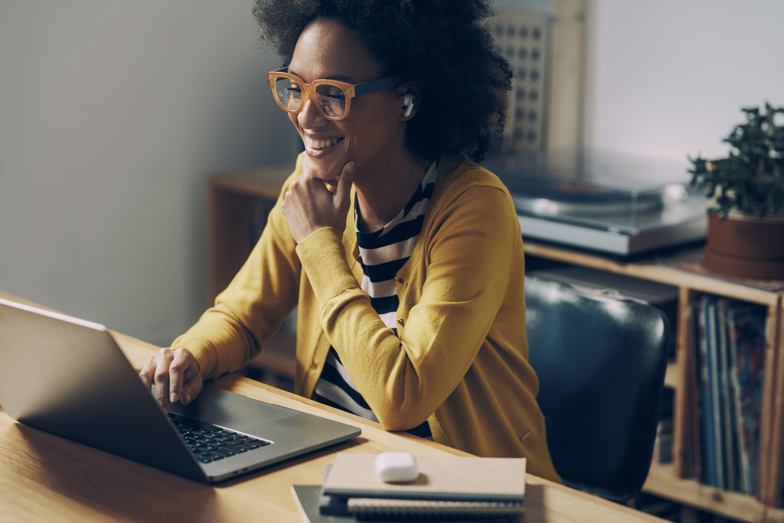 Woman wearing glasses smiles at the computer while working