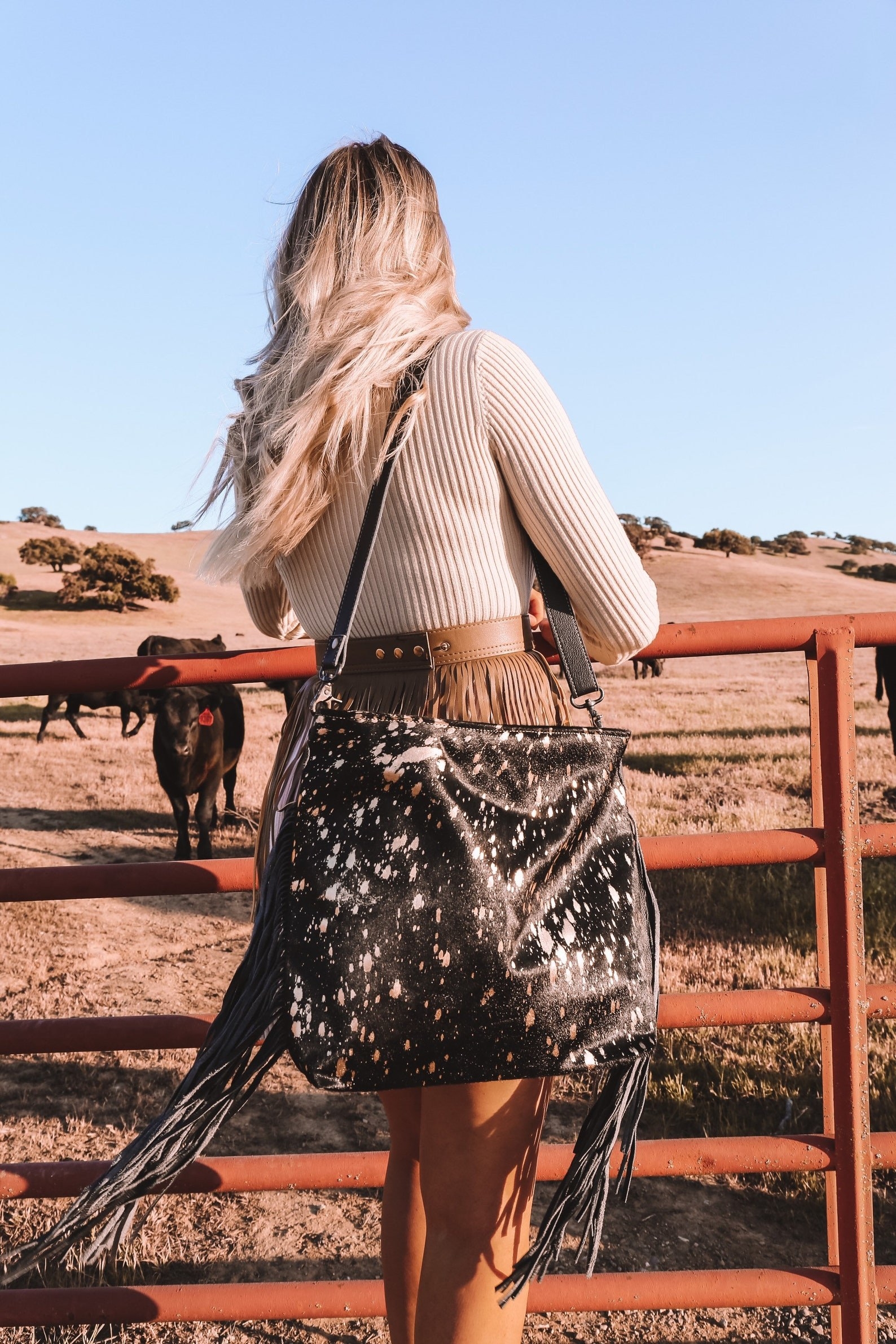 model wearing the messenger style cowhide bag with long fringe accents