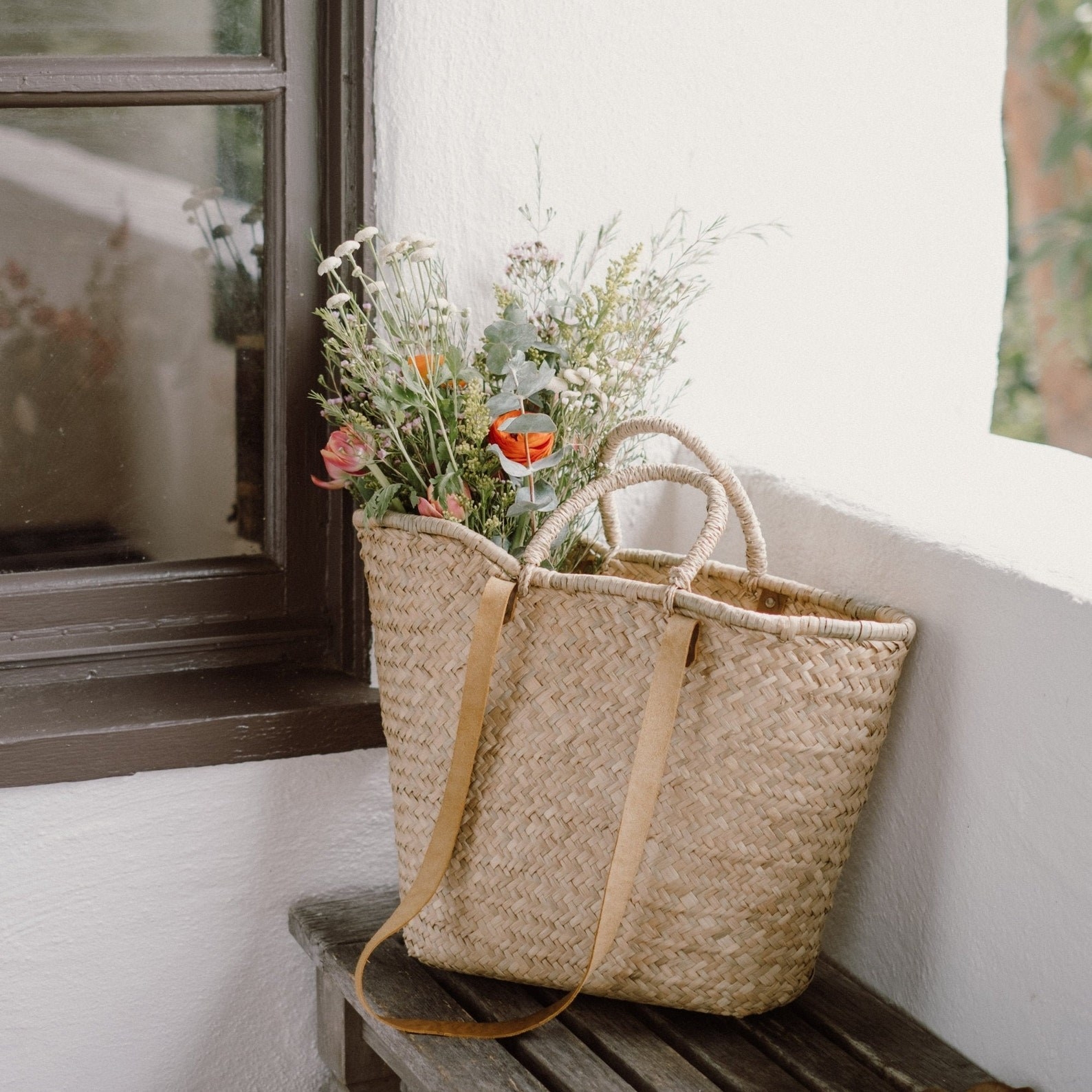 woven market style bag with a bouquet of flowers in it