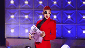 Drag Race contestant carrying a giant clutch purse