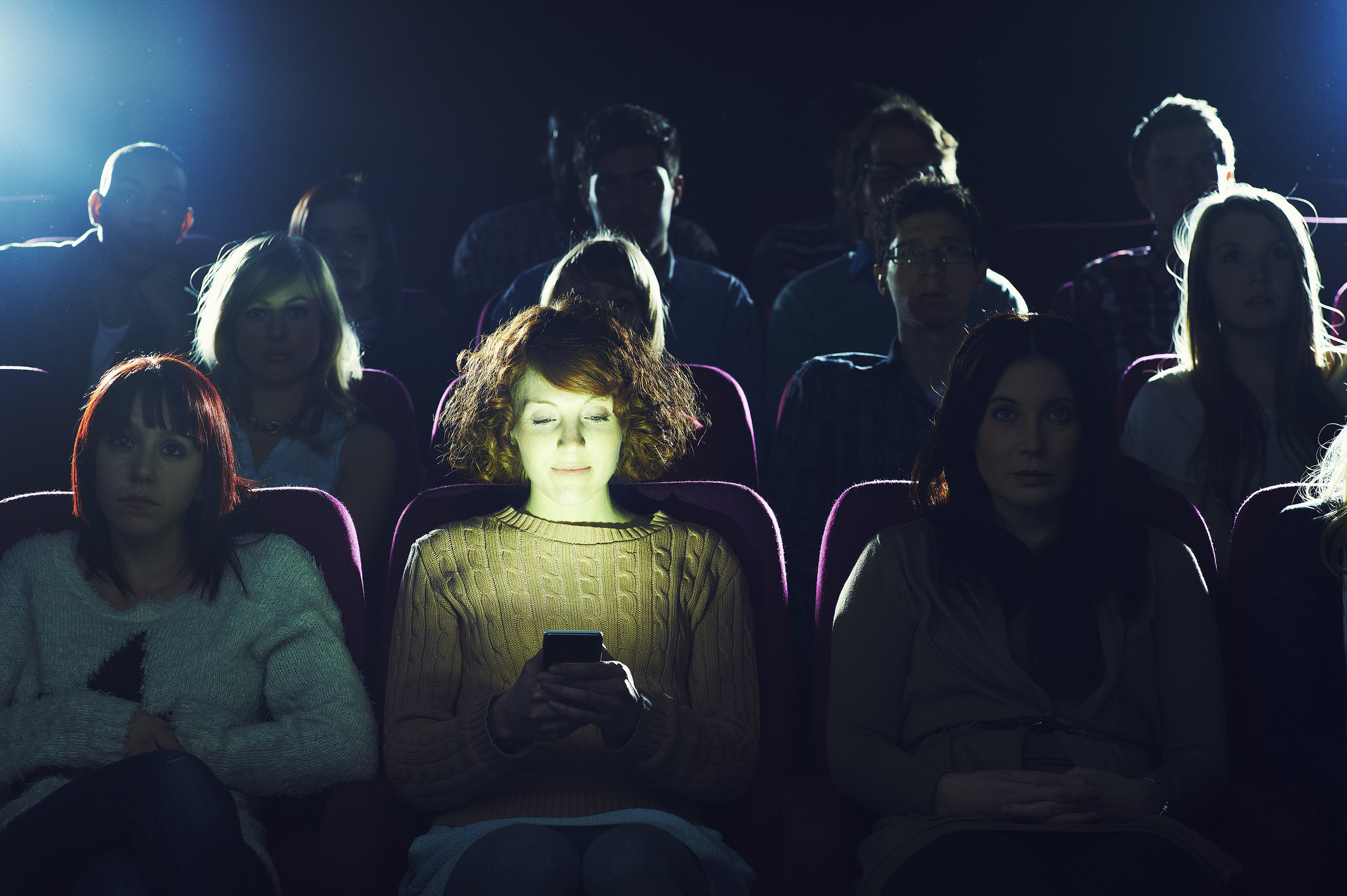 woman using her phone in a dark movie theater