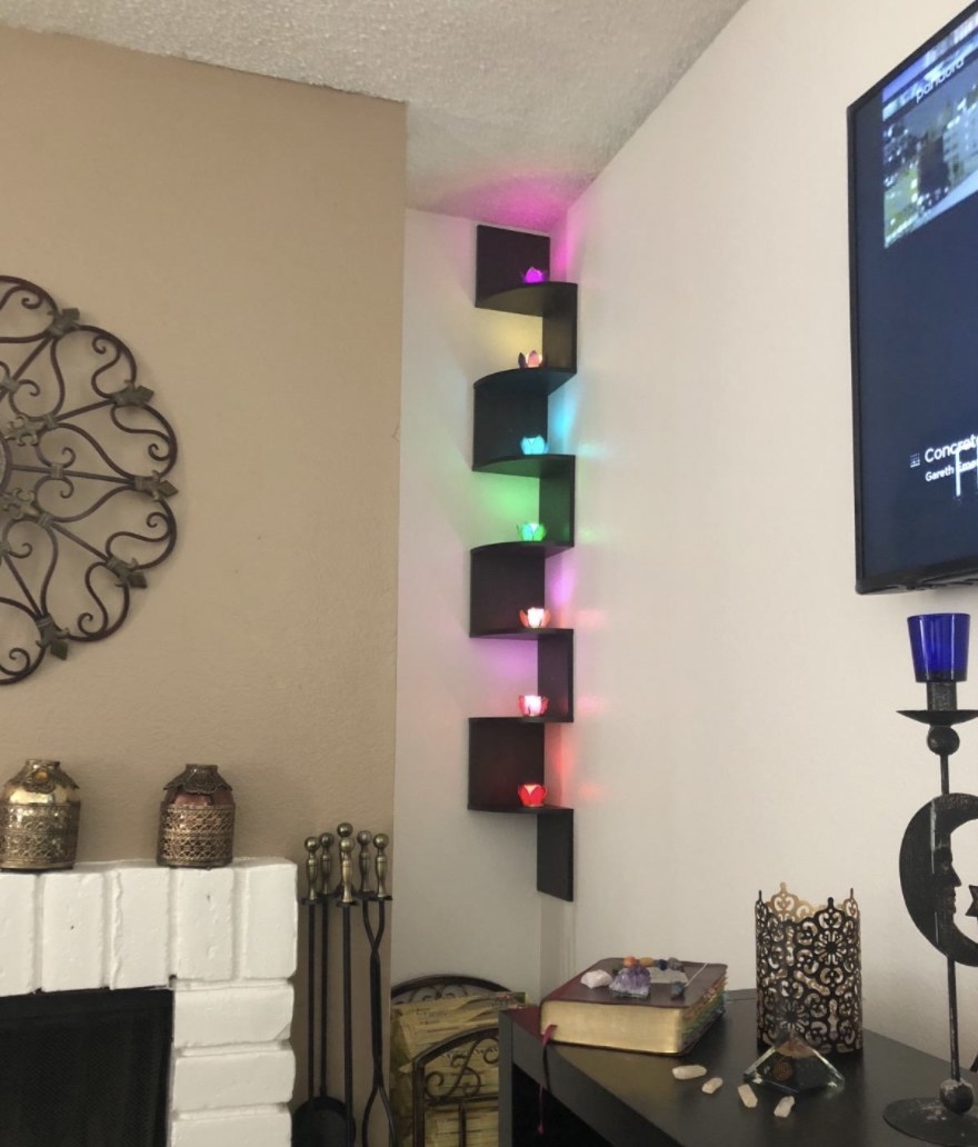 A reviewer&#x27;s photo of the wall shelf holding multi-colored crystal lights
