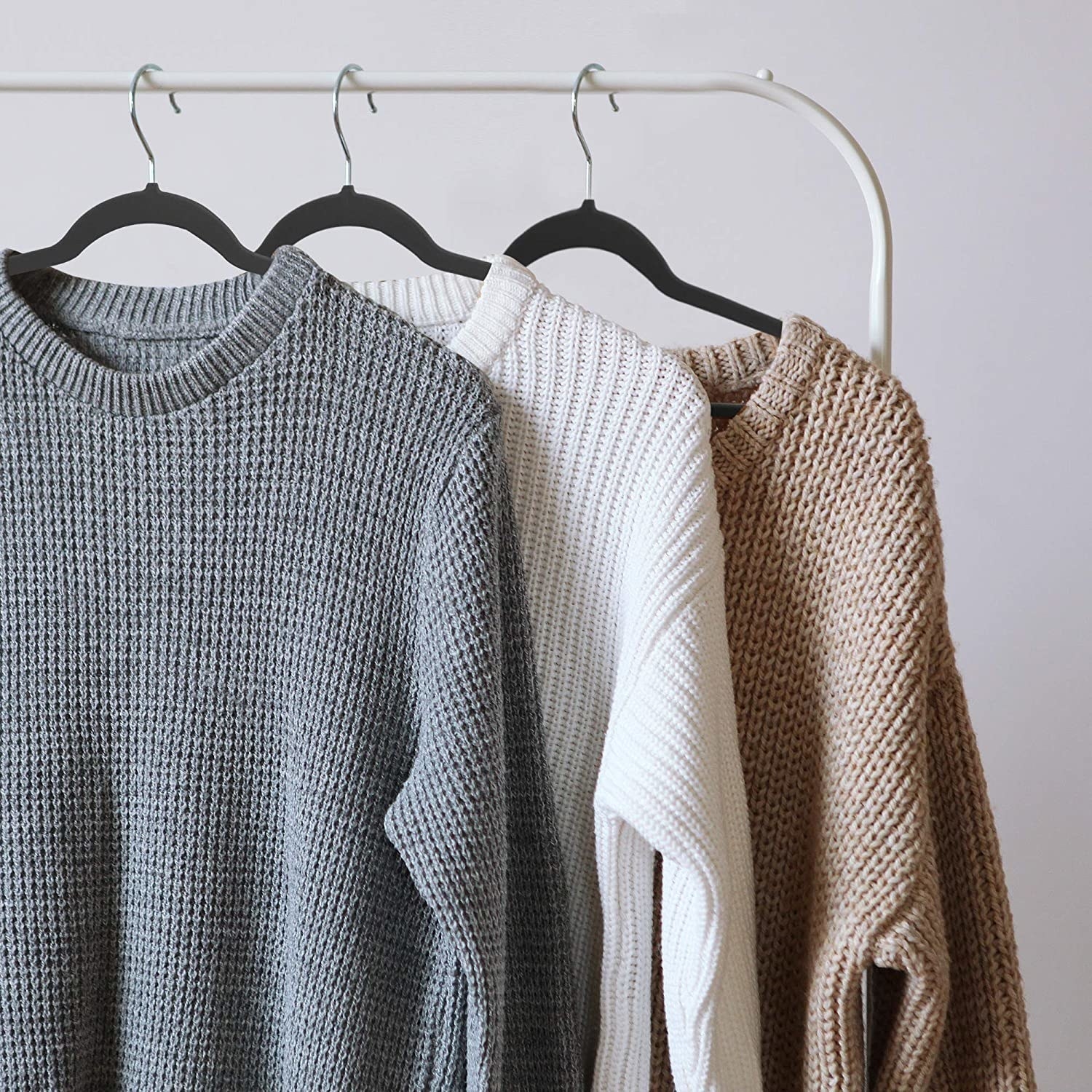 Sweaters hanging on a clothing rack with the velvet hangers