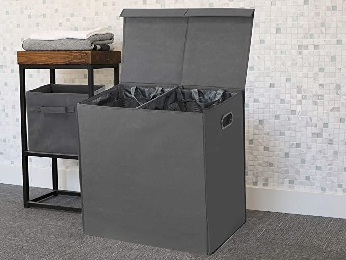 A laundry hamper in a laundry room propped open revealing the two separate compartments inside