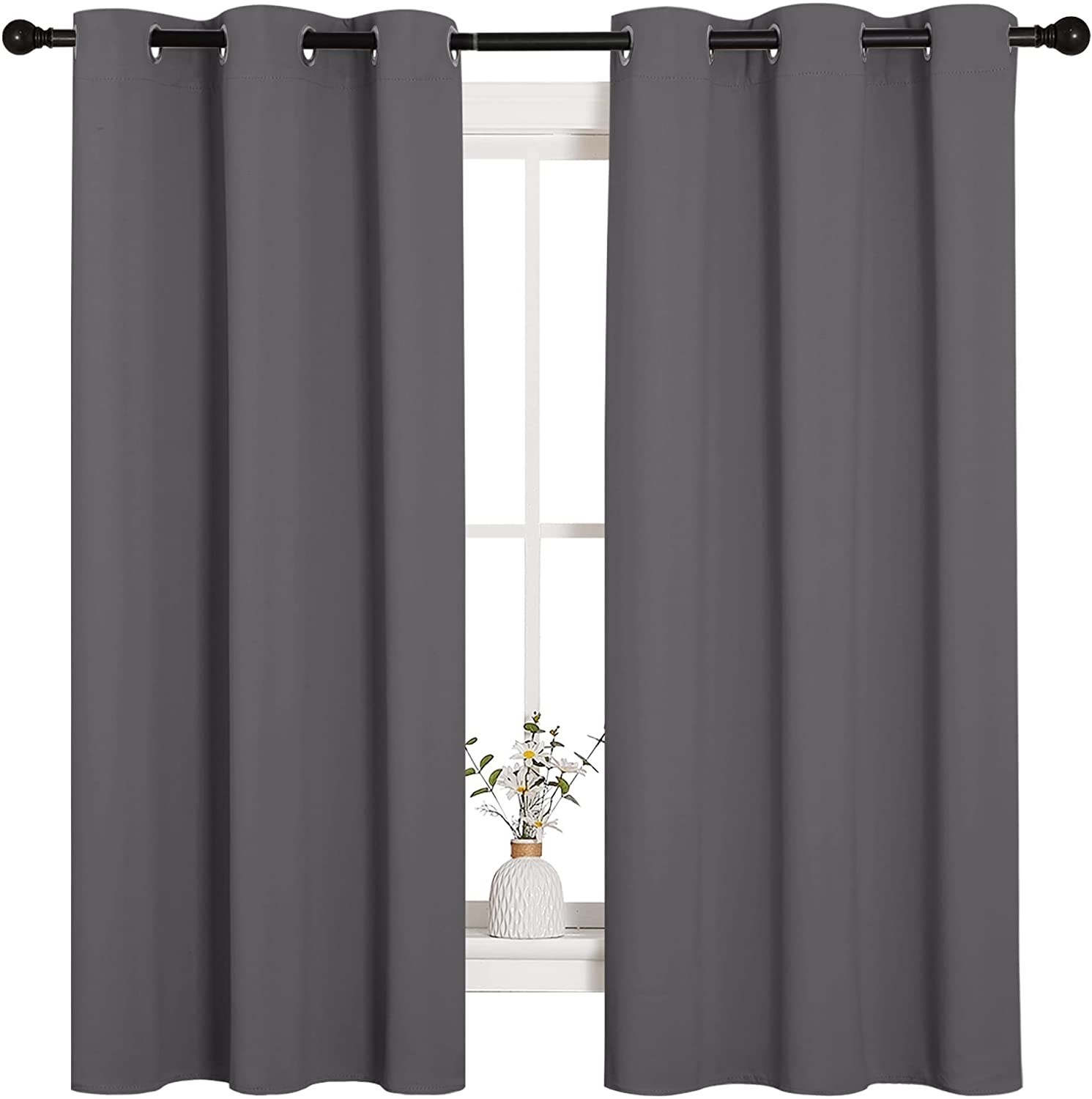 A set of curtains on a plain window with a vase of flowers in the middle