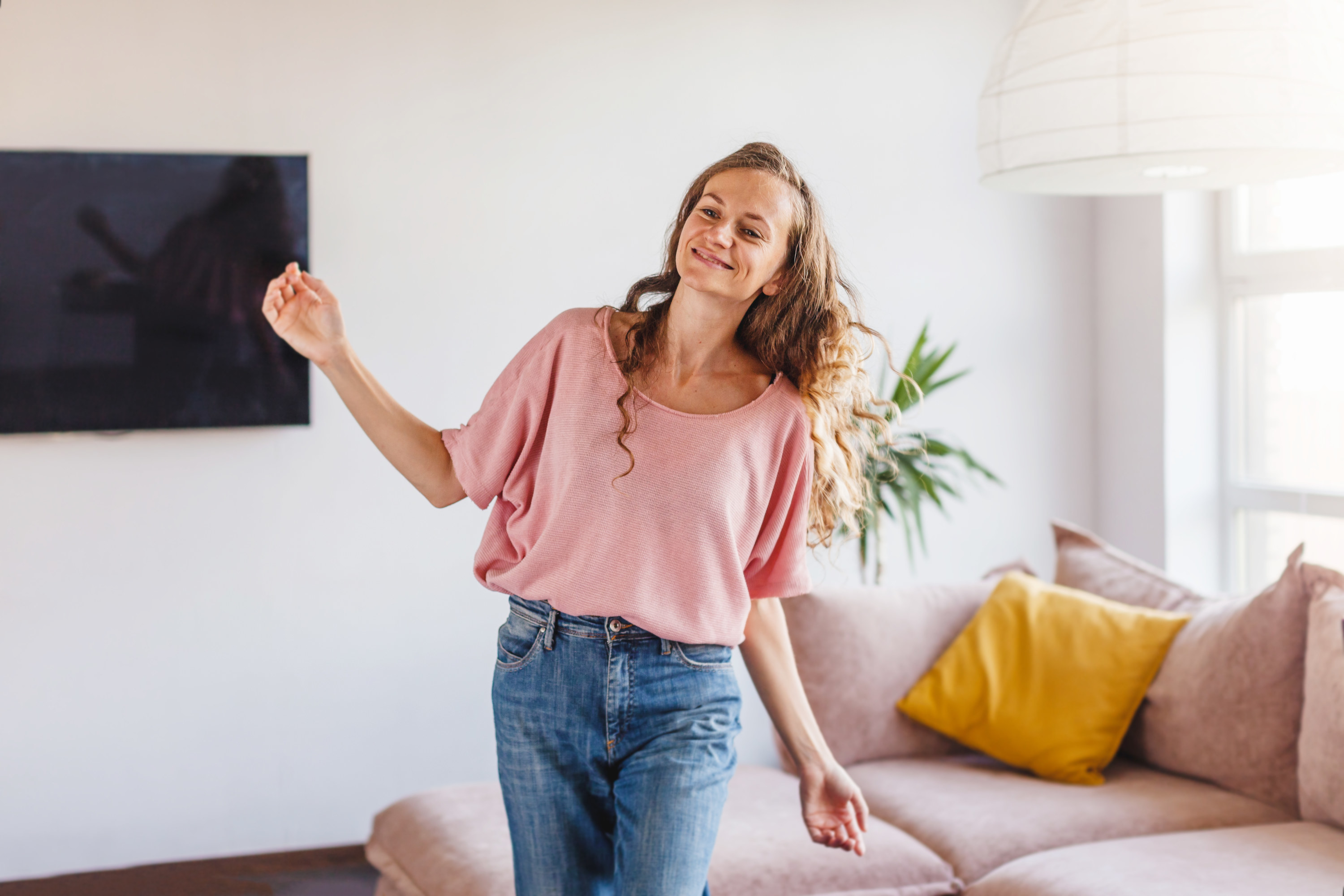 A girl in a pink shirt dances alone in her living room