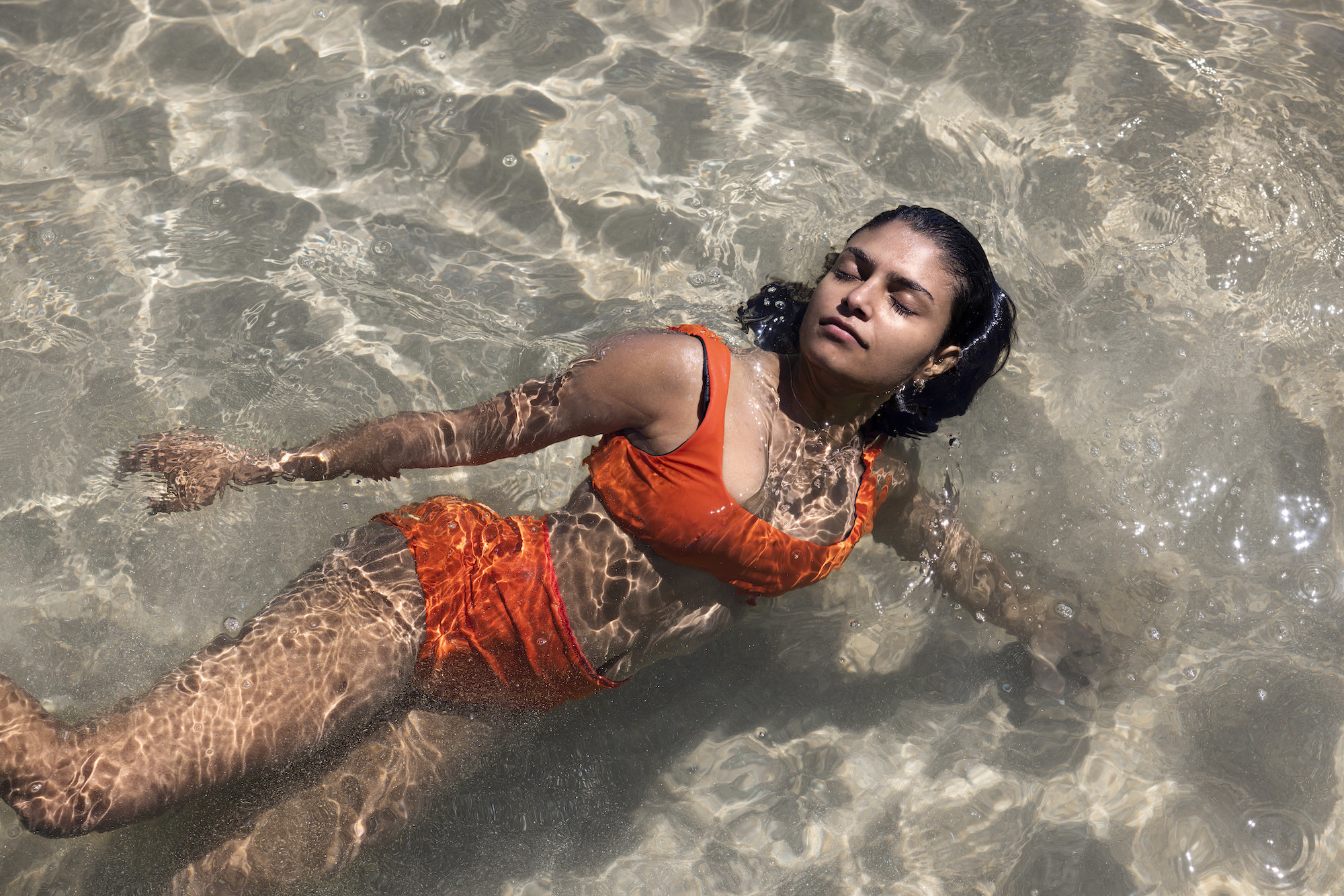 A model swimming in the ocean while wearing the period friendly bikini