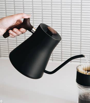 a model pouring hot water into a pour-over coffee cup.