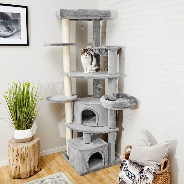 grey cat tree with a white and black cat on it