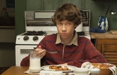 A young boy sits at a table between his parents