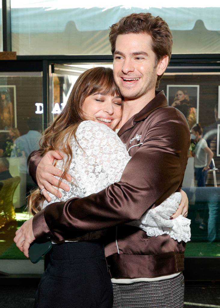 Dakota Johnson and Andrew Garfield hugging at a press event