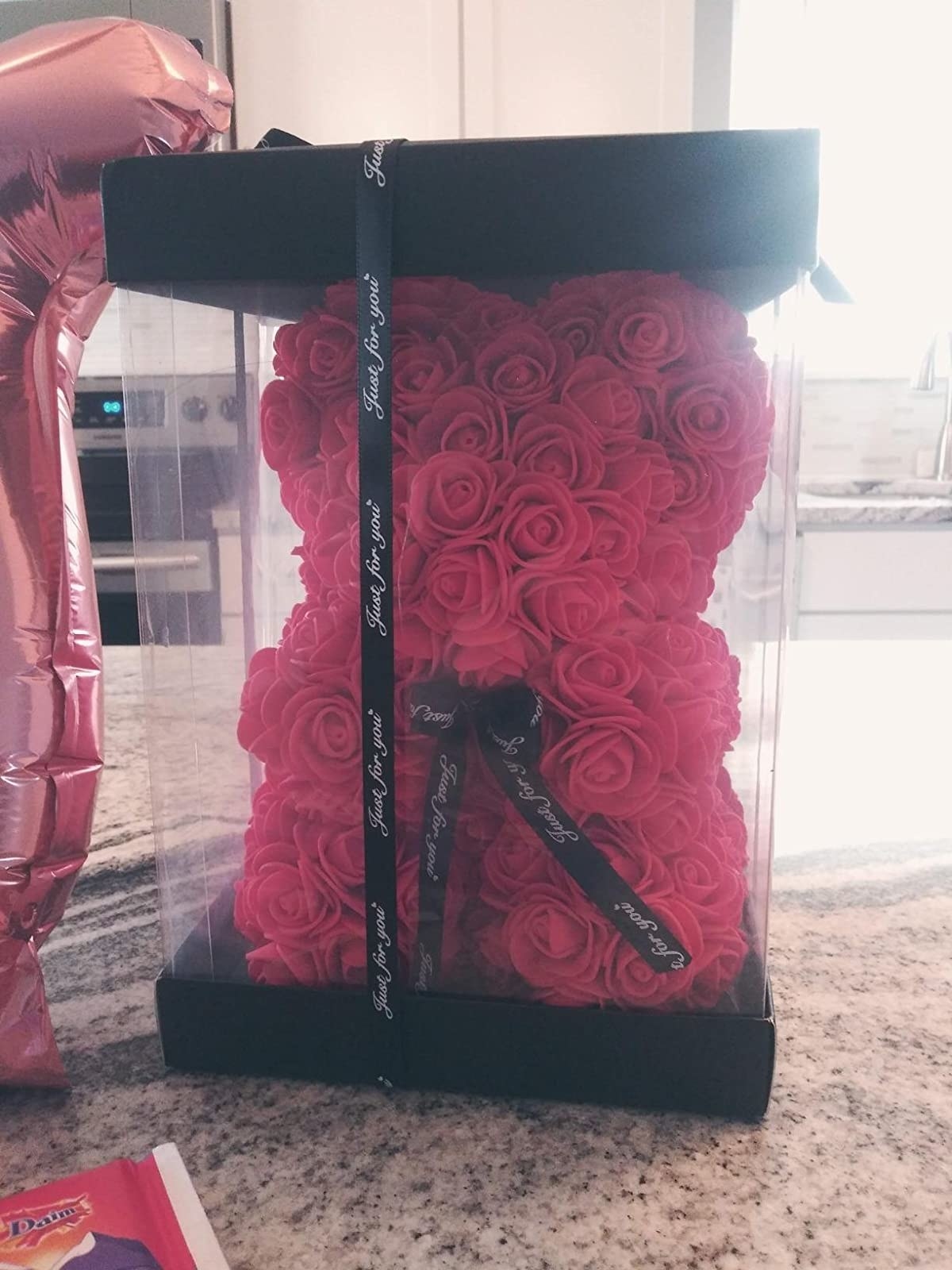 reviewer&#x27;s photo of the rose bear in a black box with a ribbon tied around it