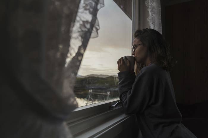 woman looking out a window longingly