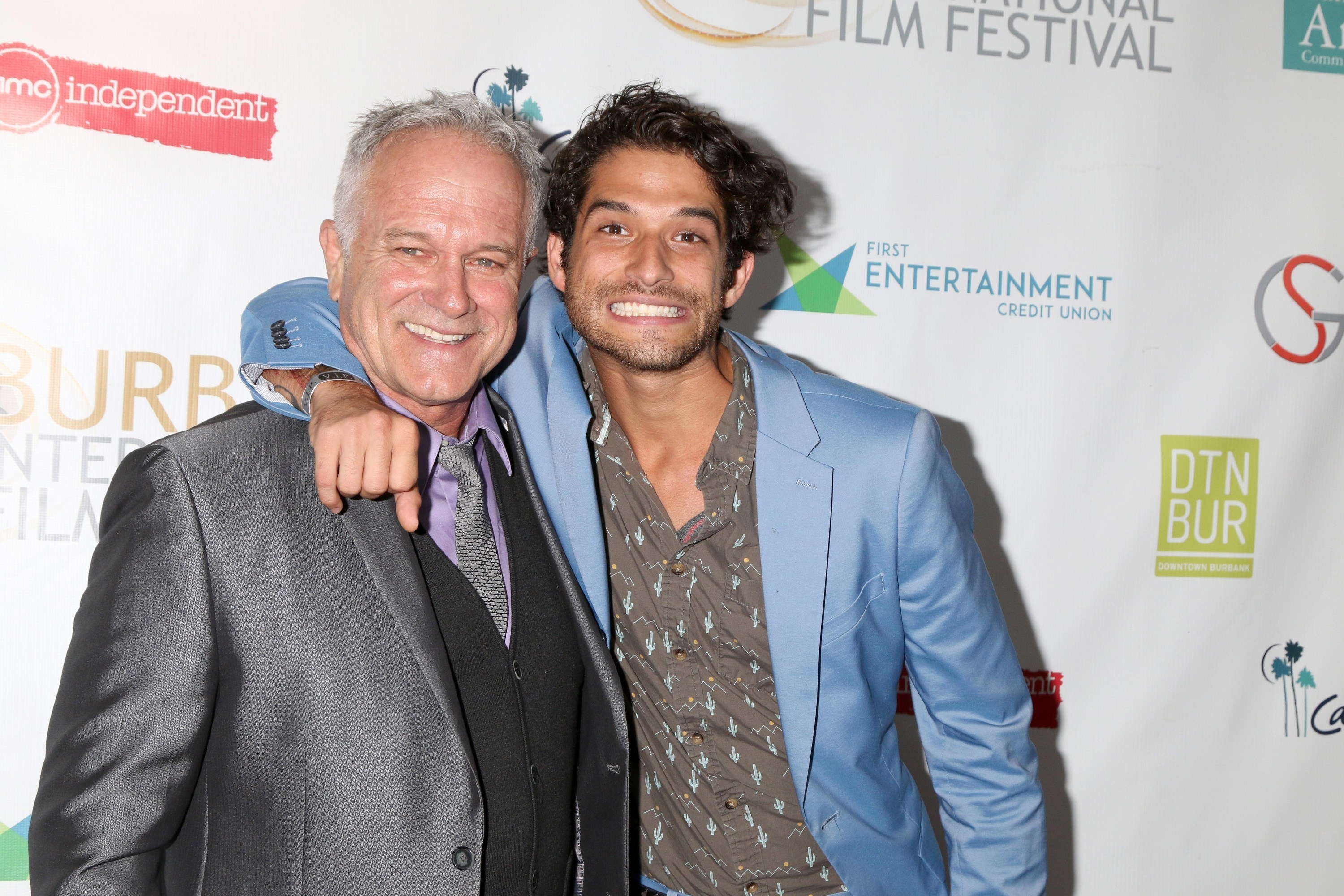 John and Tyler Posey smile together on the red carpet