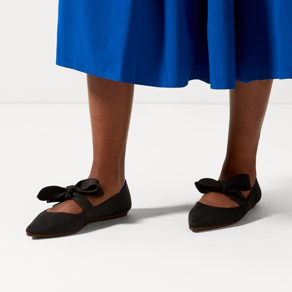 Model wearing black mary jane flats with a bow