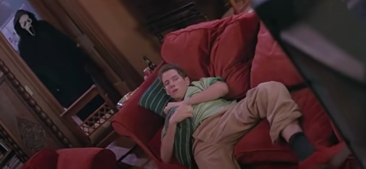 Kenny sitting on the couch watching a film while Ghostface watches him in "Scream" (1996)