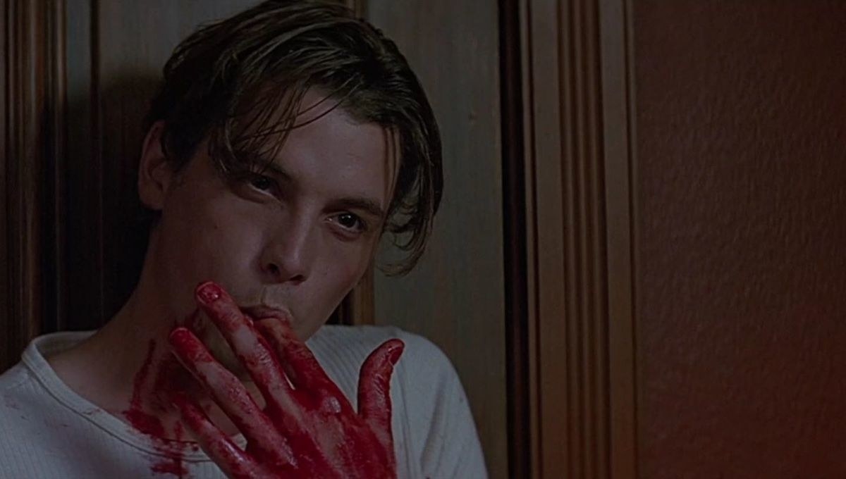 Billy Loomis standing against a door and licking the fake blood off of his fingers
