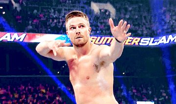 Stephen Amell pretends to shoot a arrow in WWE ring