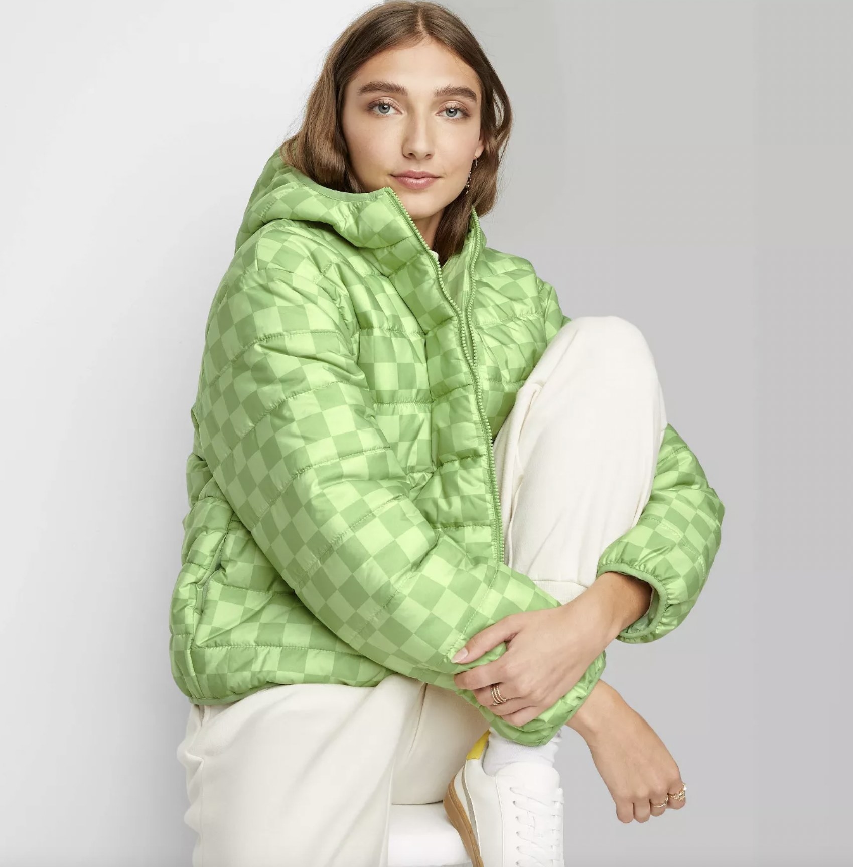 a model wearing the puffer jacket in sage green check