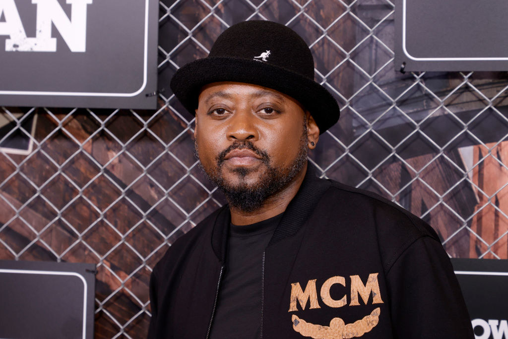 Omar Epps posing at a Starz event in an MCM jacket and a Kangol hat