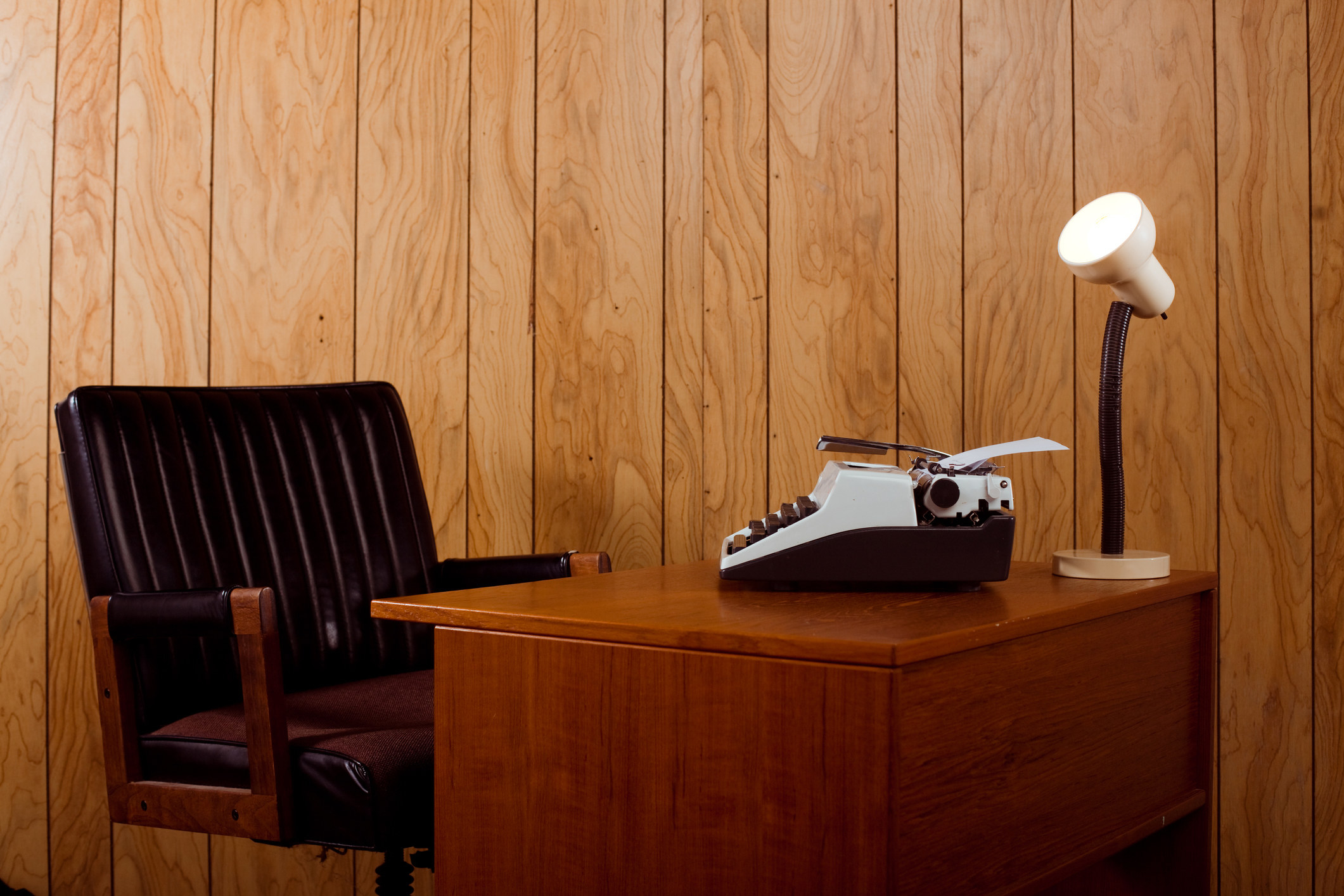 Vintage desk with a typewriter in a wood paneled room