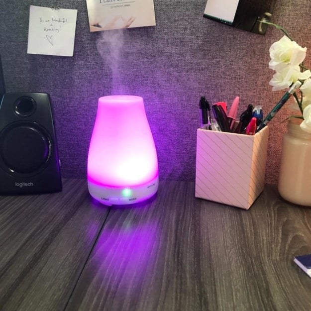 reviewer photo of the humidifier glowing pink-purple in someone&#x27;s cubicle