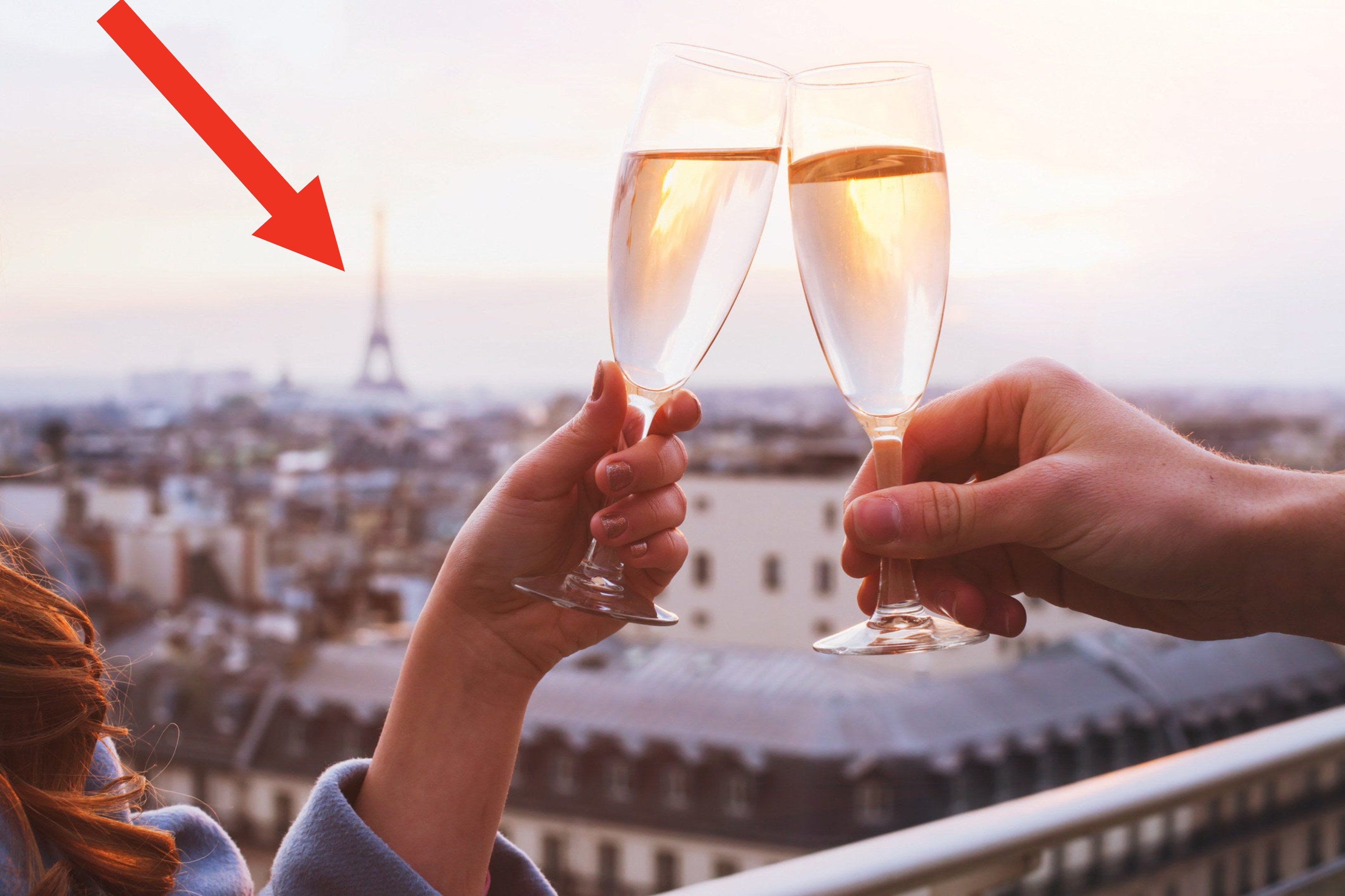 People clinking Champagne glasses with a view of the Eiffel Tower.