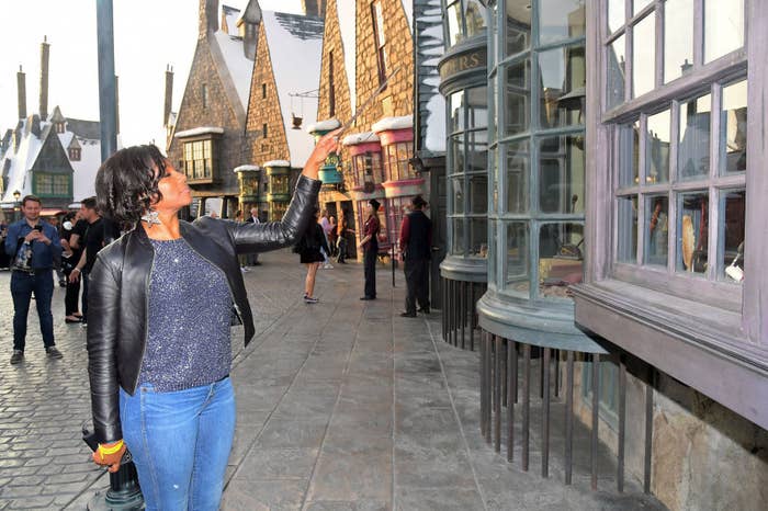 the comedian waves her wand at one of the interactive windows in Diagon Alley