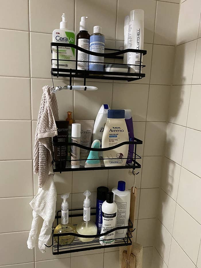 reviewer&#x27;s black shower caddies mounted to a shower wall